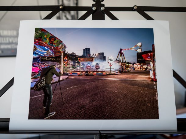 Print of a street photographer who is taking a photo of an attraction at a fair in Almere with his camera on a tripod. There are almost no visitors at the fair.